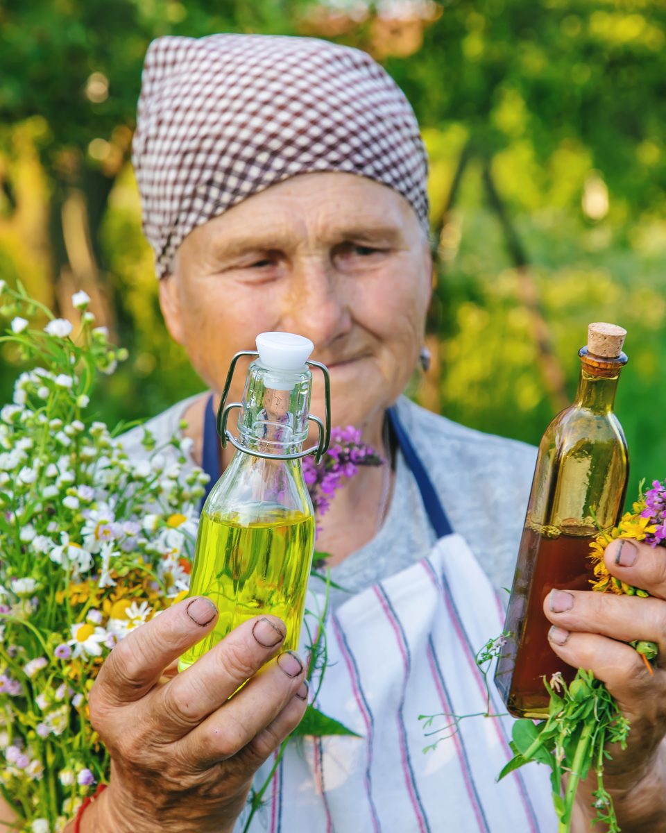 Femme âgée préparant une teinture à base de plantes, illustrant la fabrication de désherbants naturels.