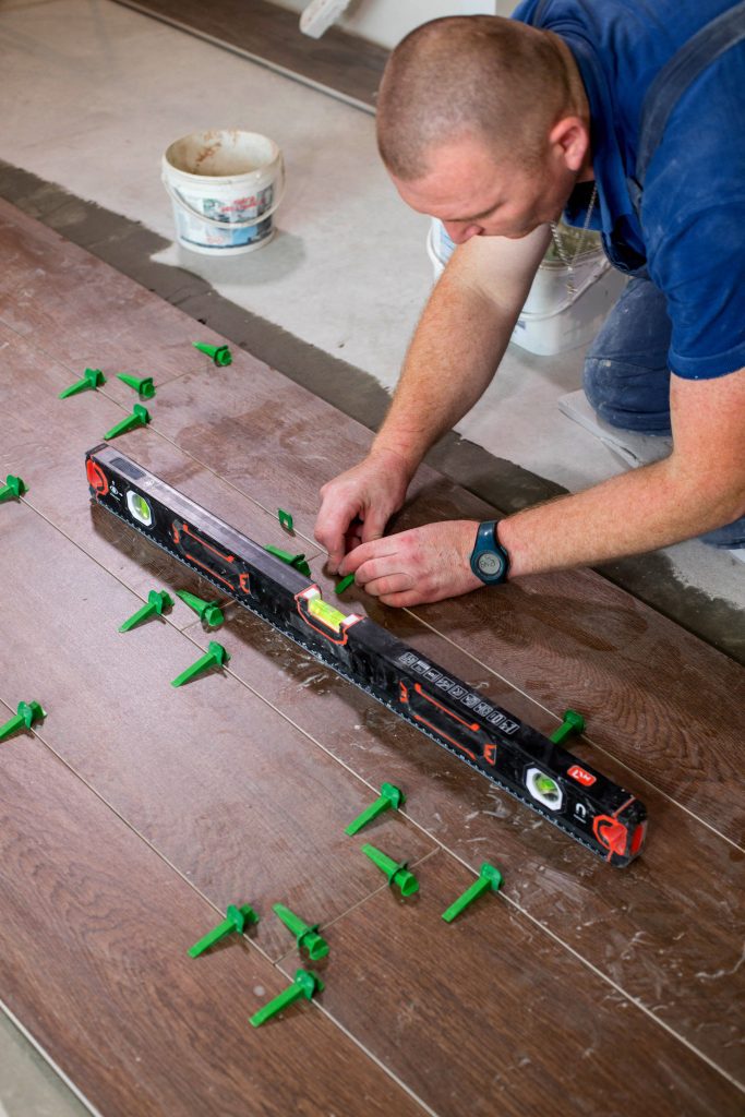 Tuiler posant des clips dans un système de nivellement de carreaux sur le sol d'une nouvelle maison.