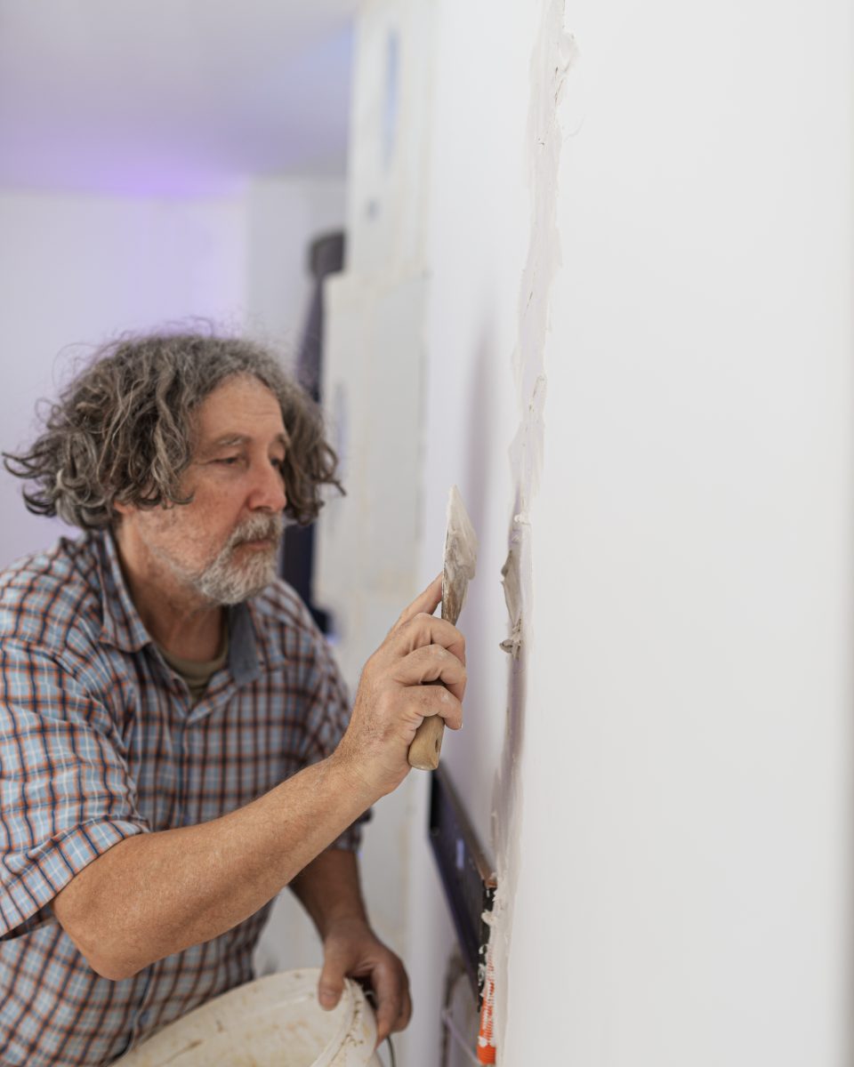 Un ouvrier en train d'enduire un mur à l'intérieur, montrant la technique d'application du plâtre.