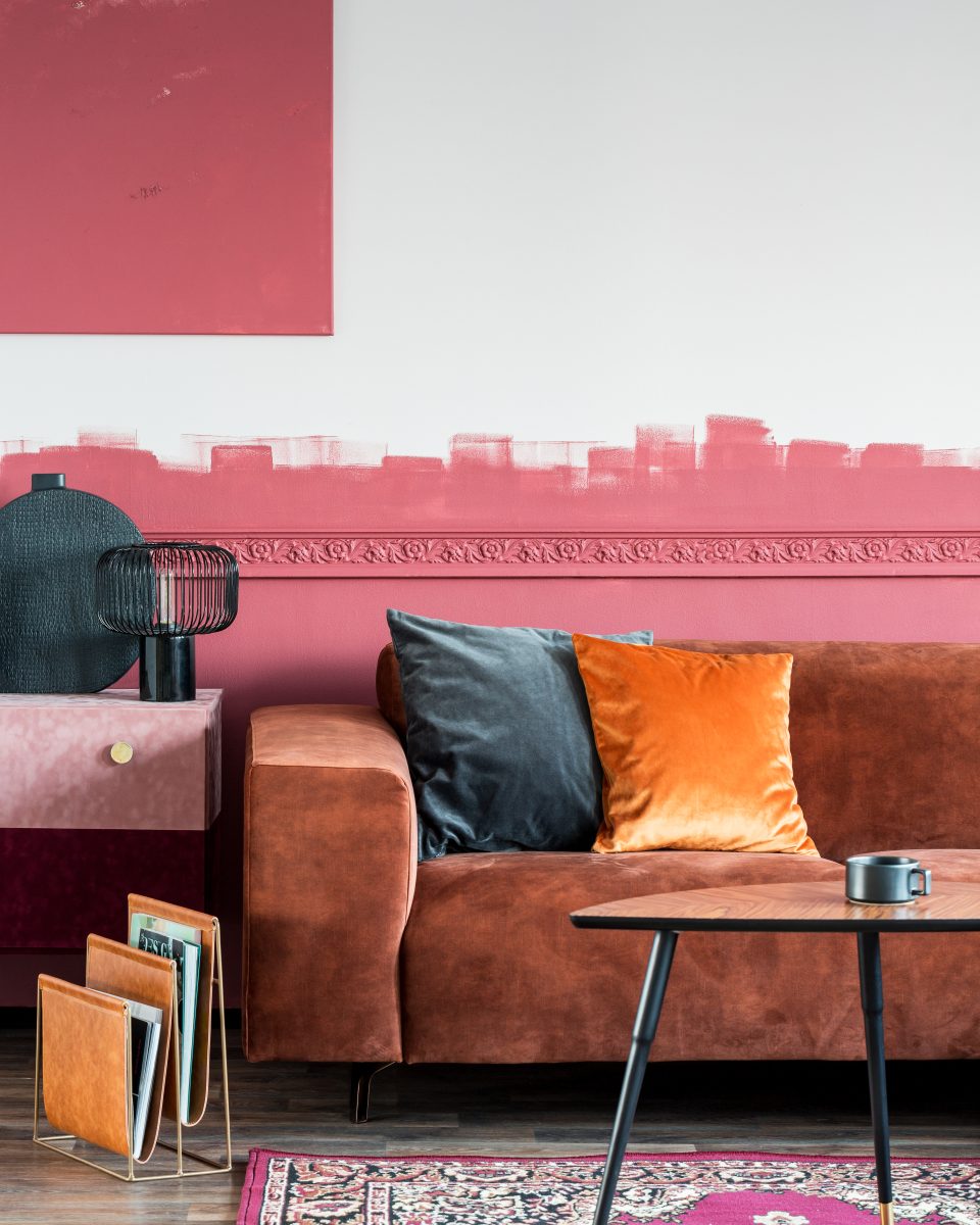 Un intérieur de salon moderne avec un canapé marron et des coussins orange, illustrant des tendances de décoration intérieure.