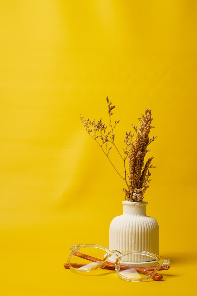 Vase avec des fleurs séchées sur un fond jaune, apportant une ambiance chaleureuse et esthétique.